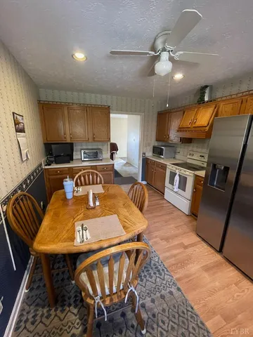 a kitchen with stainless steel appliances granite countertop a sink a stove a dining table and chairs with the cabinets
