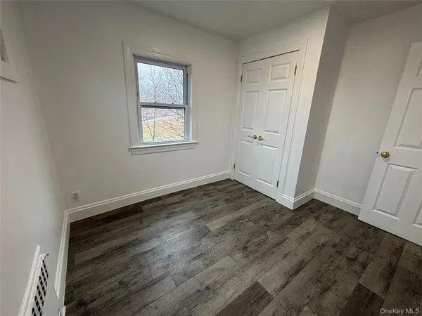 an empty room with wooden floor and window