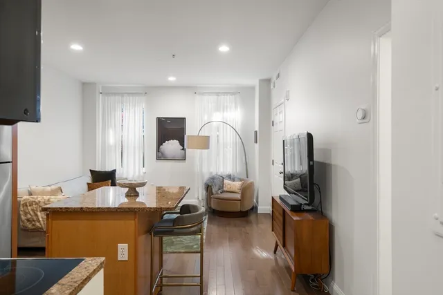a living room with furniture a flat screen tv and a refrigerator