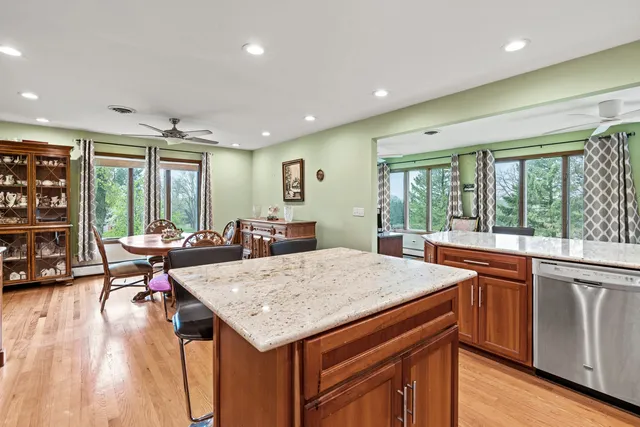 a living room with stainless steel appliances granite countertop a table chairs and a large window