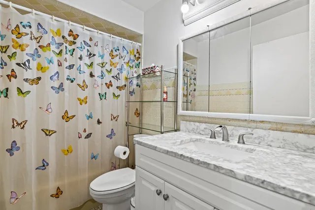 a bathroom with a granite countertop sink a toilet and a mirror