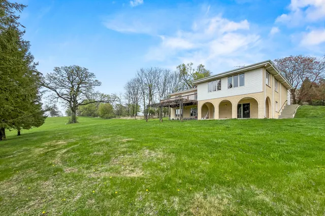 a view of a white house with a big yard and large trees