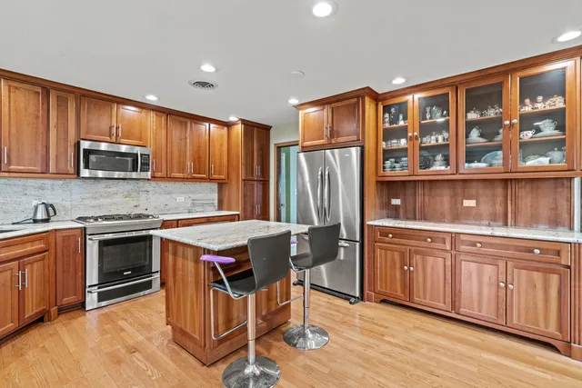 a kitchen with stainless steel appliances granite countertop a stove top oven a sink dishwasher and a refrigerator with wooden cabinets