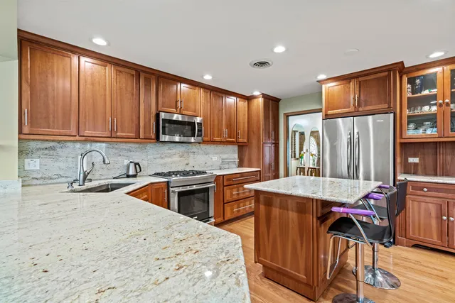 a kitchen with stainless steel appliances granite countertop a stove top oven a sink dishwasher and cabinets with wooden floor