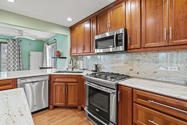 a kitchen with stainless steel appliances granite countertop wooden cabinets stove top oven and sink