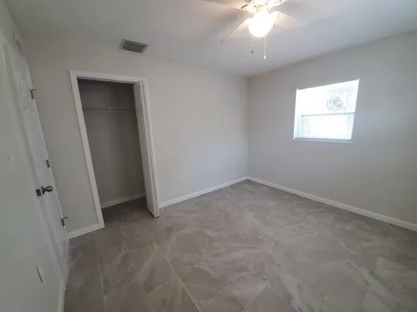 an empty room with a fan & a window