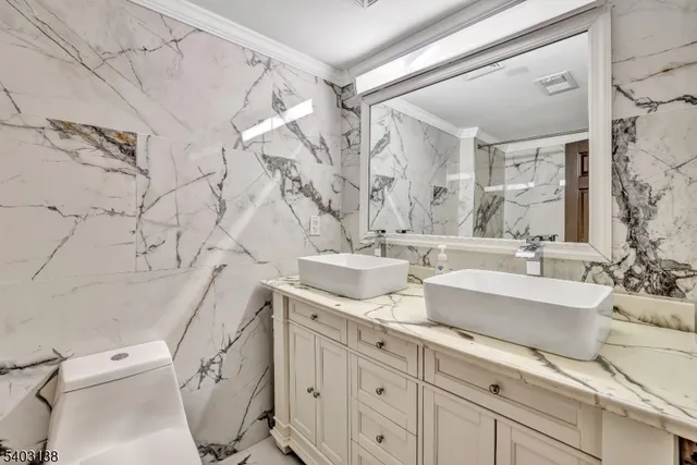 a spacious bathroom with double vanity sink a mirror and a toilet