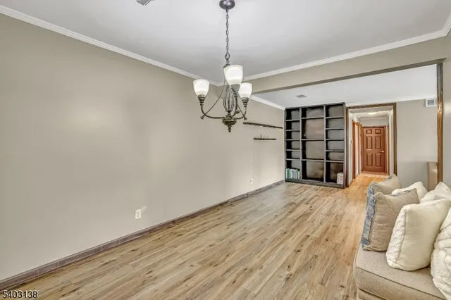 a view of a livingroom with a chandelier fan and wooden floor