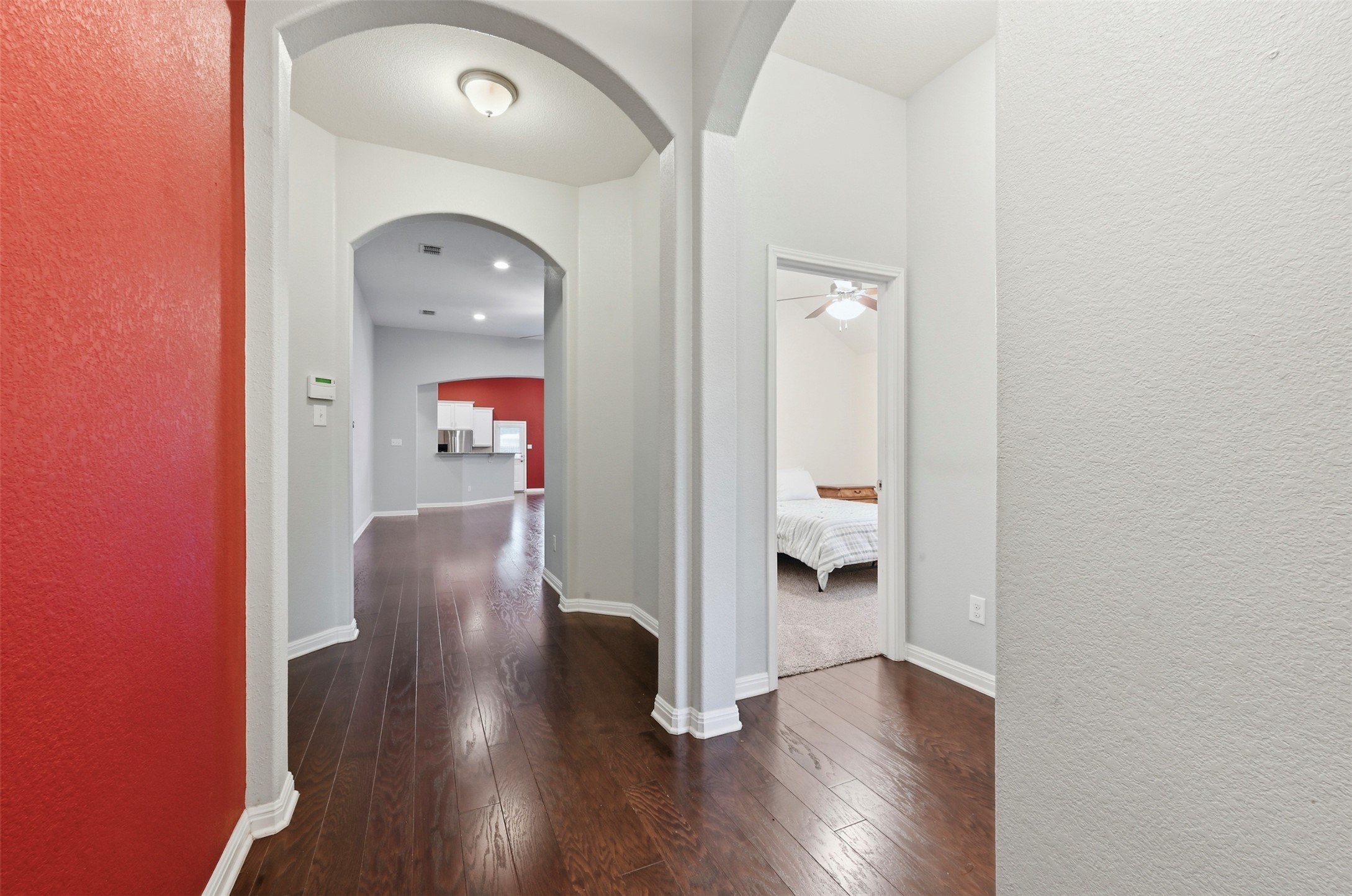 13116 Alans Way Manchaca, TX 78652 - Photo 3 of 25 Hallway featuring dark wood-finish flooring, arched doorways, and a flush-mount ceiling light