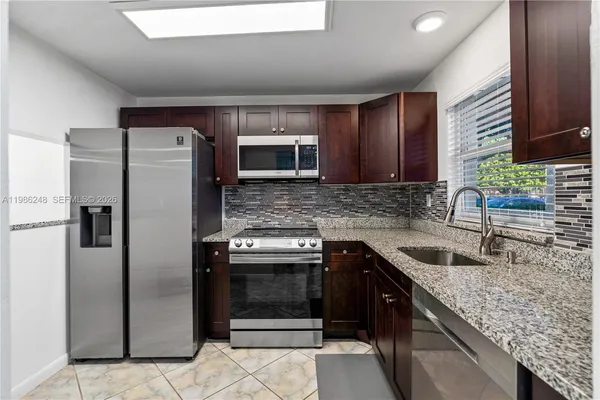 a kitchen with stainless steel appliances granite countertop a sink stove and refrigerator