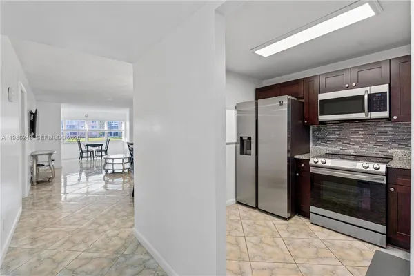 a kitchen with granite countertop a refrigerator and a stove top oven