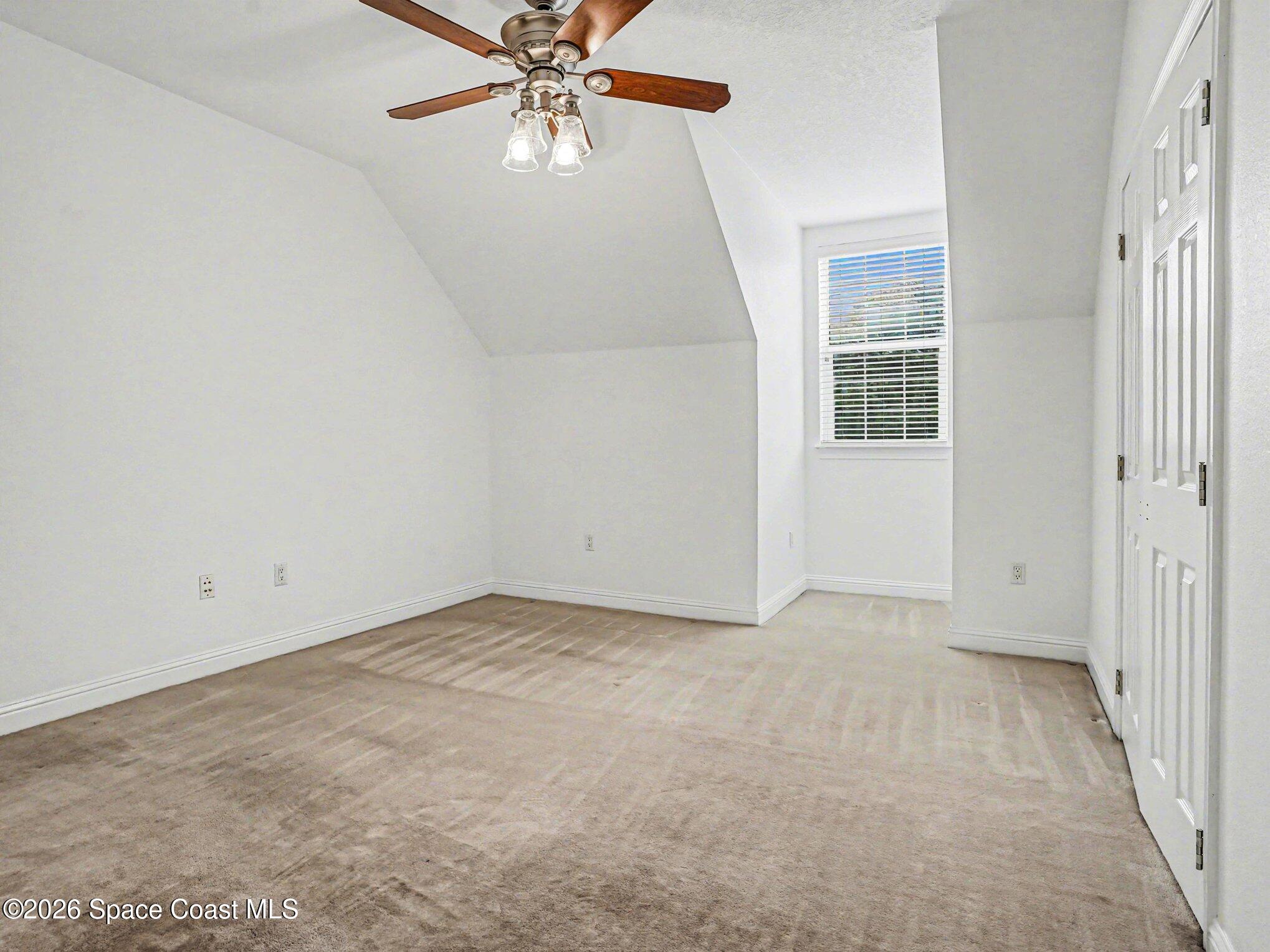 11940 Kirby Smith Road Orlando, FL 32832 - Photo 19 of 39 an empty room with a chandelier fan and windows