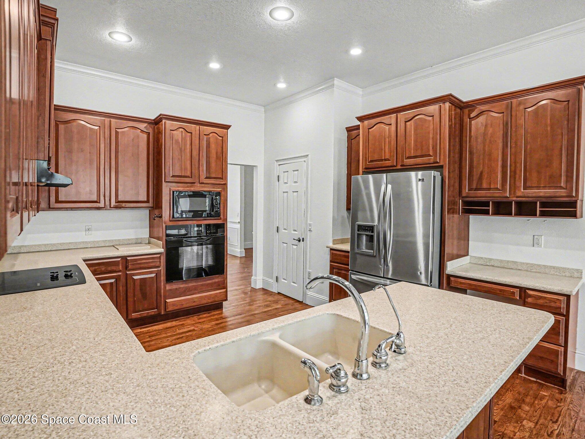 11940 Kirby Smith Road Orlando, FL 32832 - Photo 4 of 39 a kitchen with stainless steel appliances granite countertop a refrigerator a stove and a sink with wooden cabinets