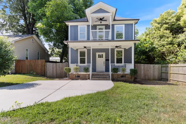 a view of a house with a yard and wooden fence