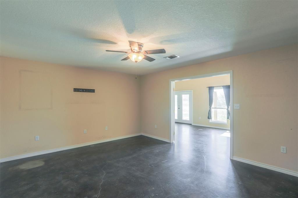 32471 Highway 108 Mingus, TX 76463 - Photo 12 of 40 Empty room featuring finished concrete flooring, visible vents, a ceiling fan, a textured ceiling, and baseboards