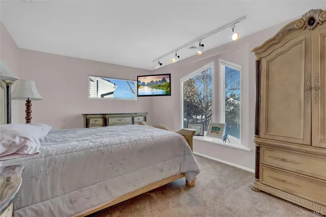 a bedroom with a bed a mirror and a large window with the outer view