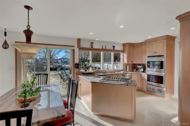 a kitchen with stainless steel appliances kitchen island granite countertop a refrigerator a stove top oven a dining table and chairs with wooden floor