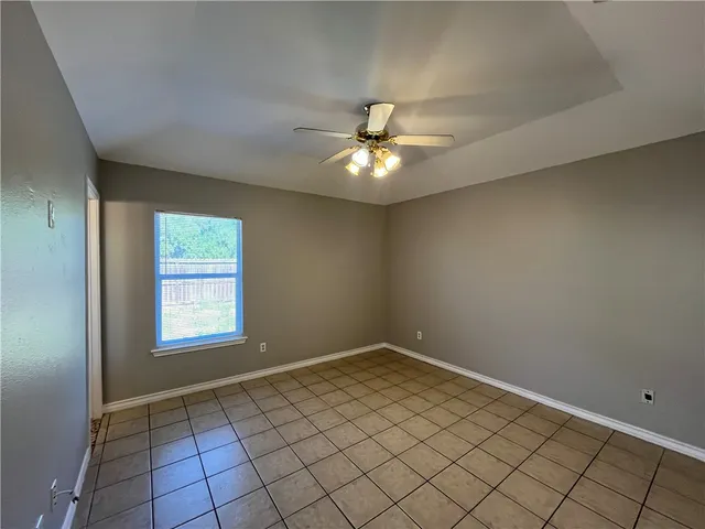 an empty room with windows and ceiling fan