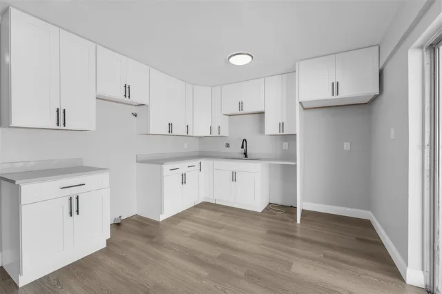 a kitchen with granite countertop white cabinets and wooden floor
