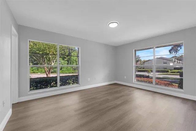 an empty room with wooden floor and windows