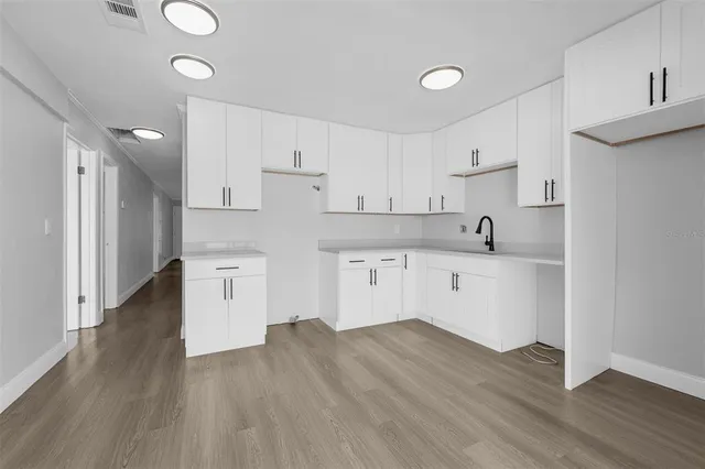 a kitchen with wooden floors and white cabinets