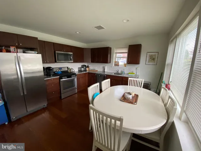 a kitchen with a refrigerator a stove a microwave a dining table and chairs