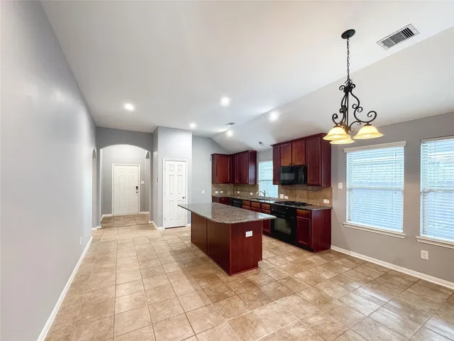 a open kitchen with kitchen island granite countertop a refrigerator a sink a stove top oven and a window