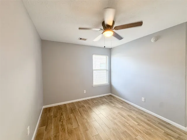 an empty room with a window and ceiling fan