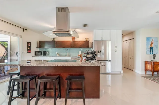 a kitchen with stainless steel appliances kitchen island granite countertop a table chairs stove and refrigerator