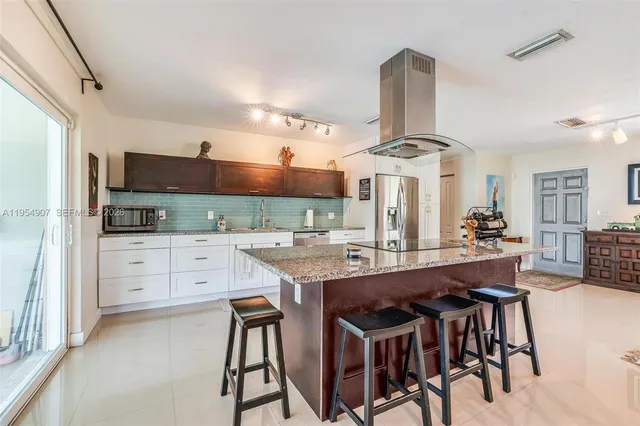 a kitchen with stainless steel appliances a dining table chairs stove and cabinets