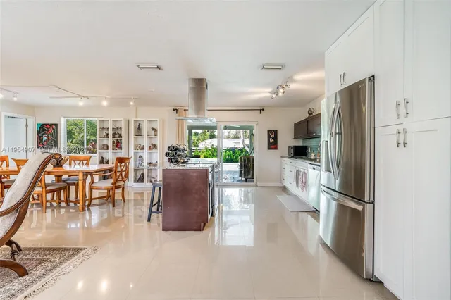 a kitchen with stainless steel appliances granite countertop a refrigerator a stove and a dining table with wooden floor