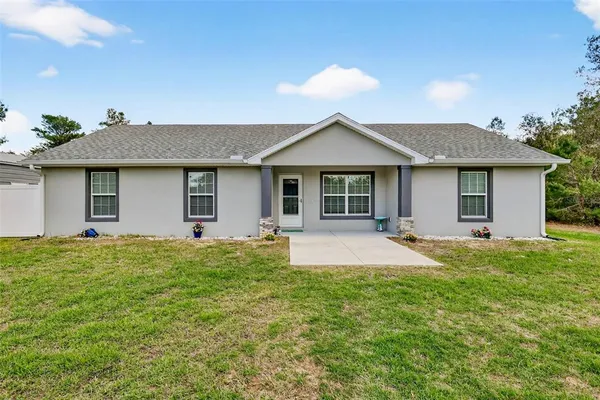 a view of a house with a patio and a yard