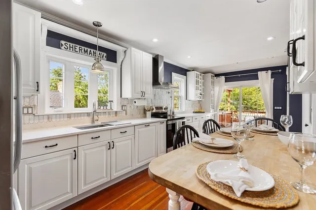 a kitchen with stainless steel appliances a dining table chairs and wooden floor