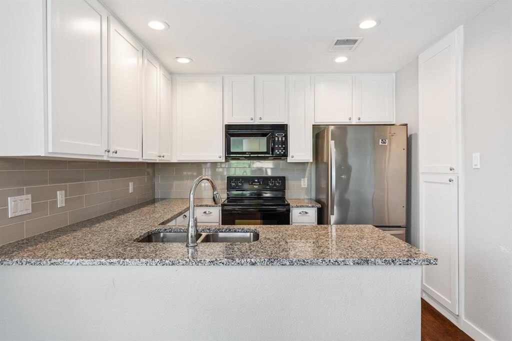 1748 Ohlen Road, Unit 22 Austin, TX 78757 - Photo 12 of 14 Kitchen featuring white shaker-style cabinetry, granite countertops, a stainless steel refrigerator, and a tile backsplash