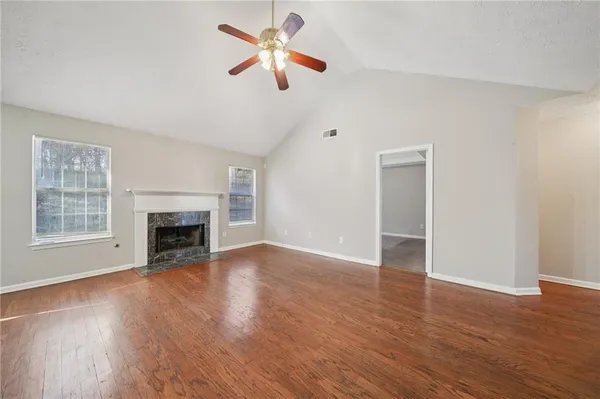 an empty room with wooden floor fan and windows
