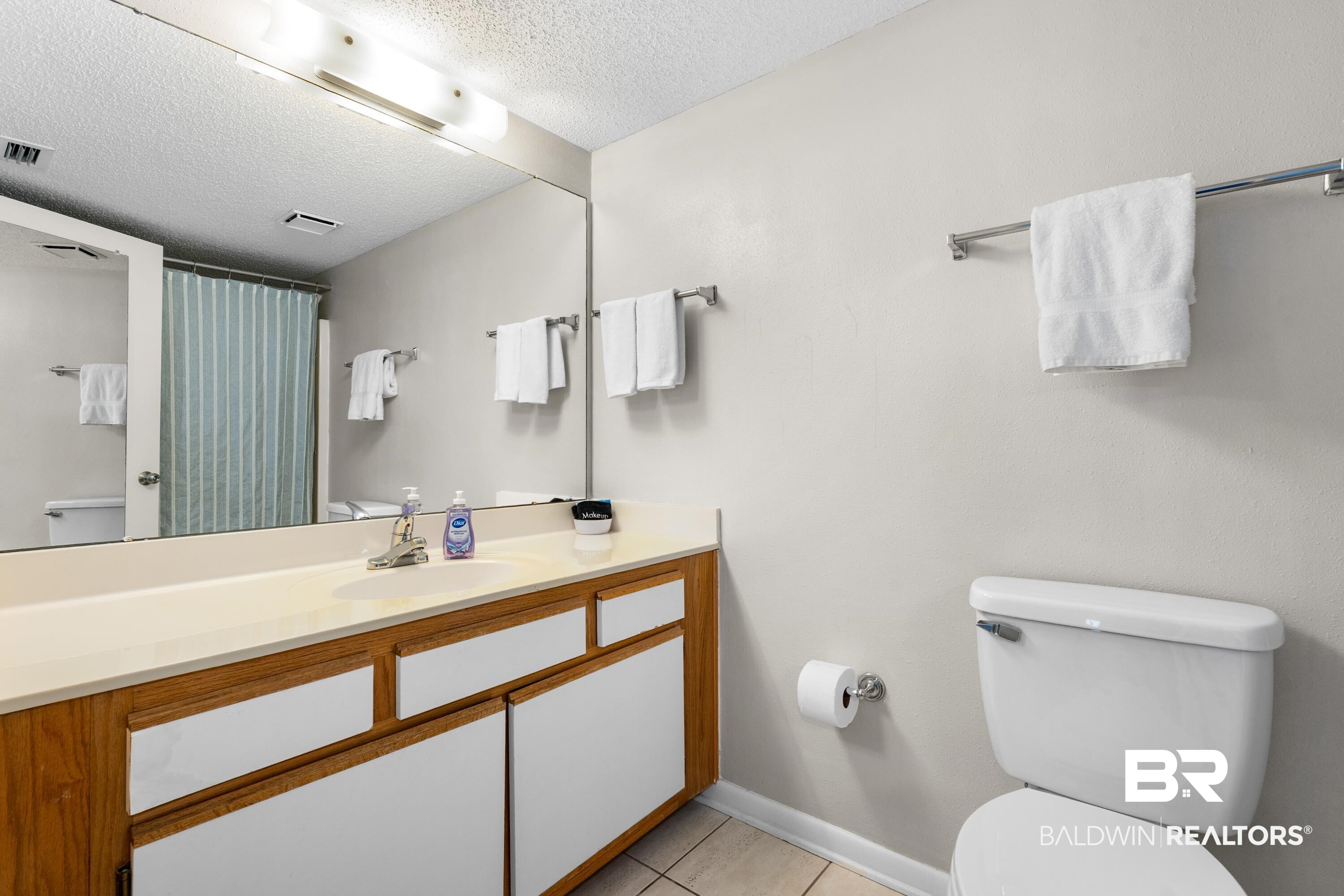 26802 Perdido Beach Boulevard, Unit 406 Orange Beach, AL 36561 - Photo 17 of 37 Bathroom with vanity, curtained shower, a textured ceiling, and light tile patterned flooring