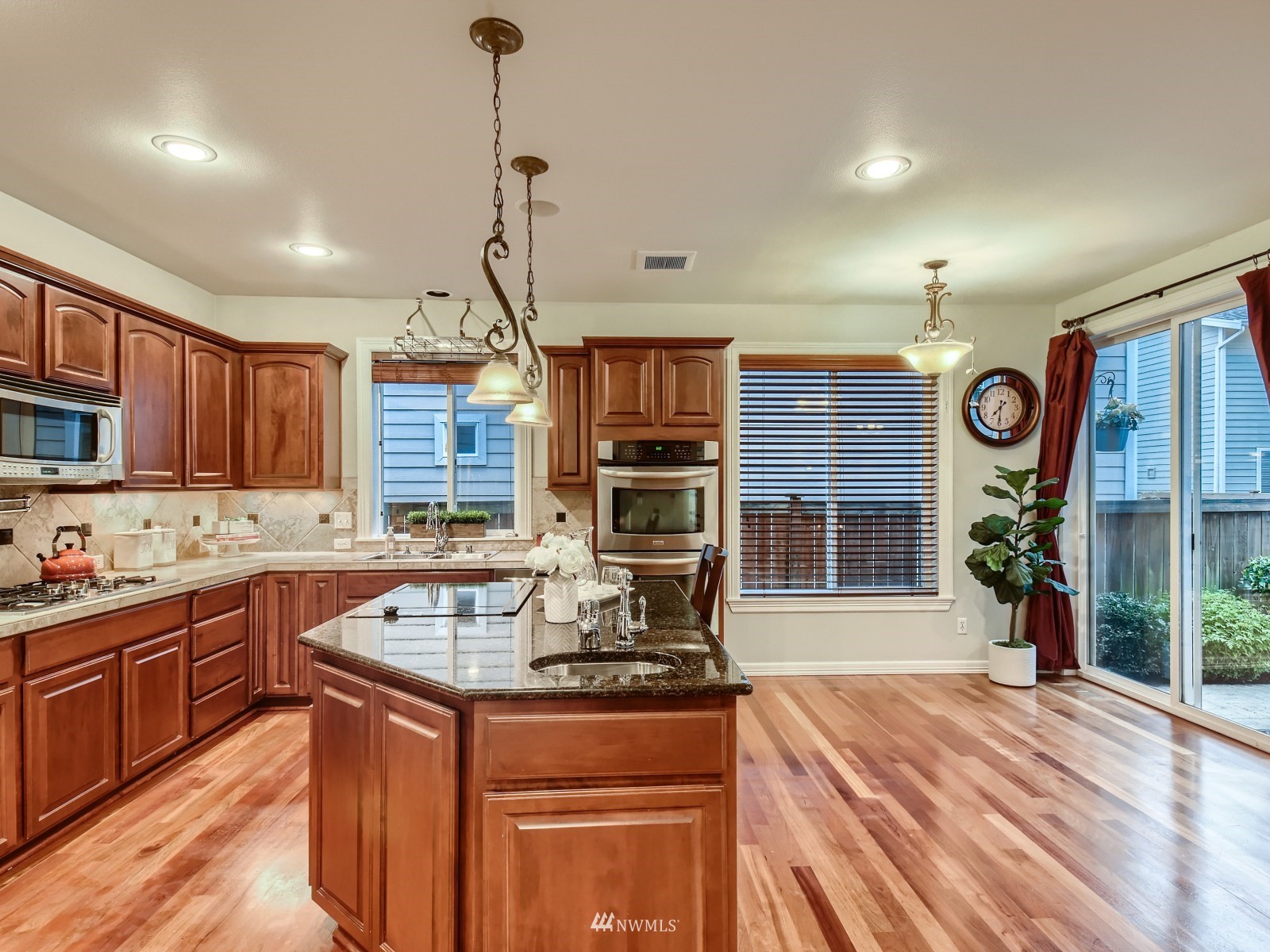 5232 Northeast 3rd Place Renton, WA 98059 - Photo 11 of 28 a kitchen with stainless steel appliances granite countertop a stove top oven a sink dishwasher a dining table and chairs with wooden floor