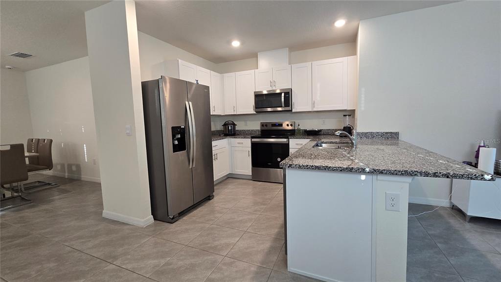 1784 Bull Hl Road Kissimmee, FL 34744 - Photo 8 of 33 a kitchen with stainless steel appliances granite countertop a sink stove refrigerator and cabinets