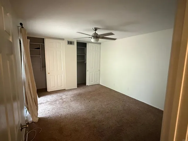 en empty room with windows and a ceiling fan