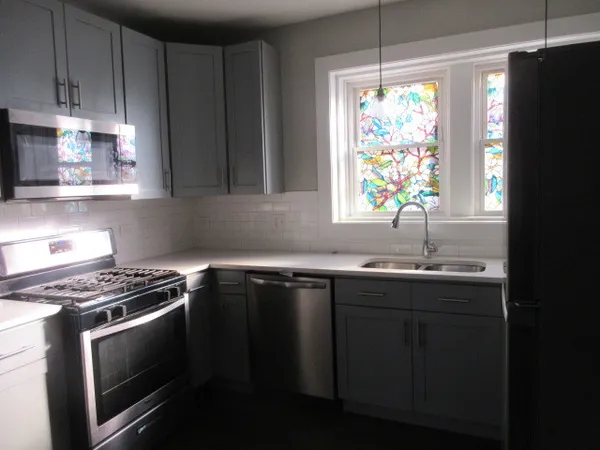 a kitchen with granite countertop a sink cabinets stainless steel appliances and a window