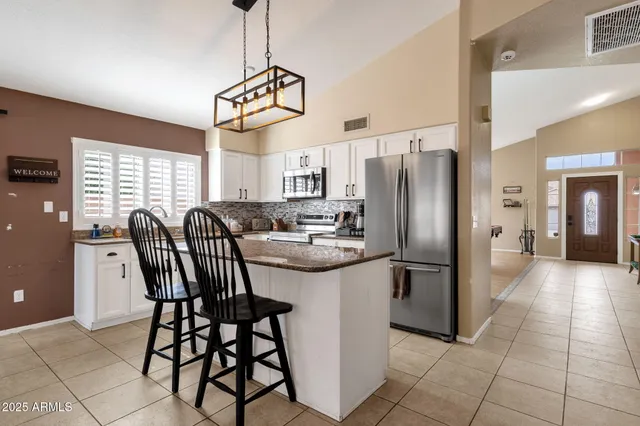 a kitchen with stainless steel appliances granite countertop a stove a sink dishwasher a refrigerator a microwave oven with a dining table and chairs