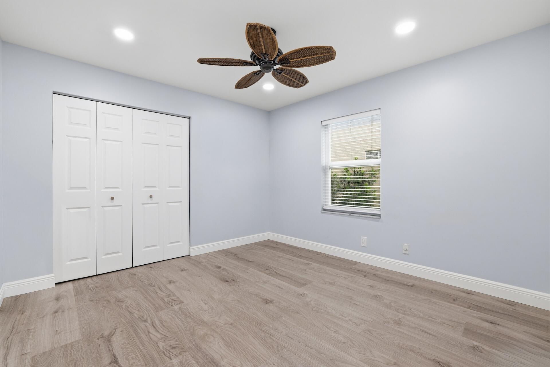 7403 Shell Ridge Terrace Lake Worth, FL 33467 - Photo 17 of 37 an empty room with wooden floor ceiling fan and windows