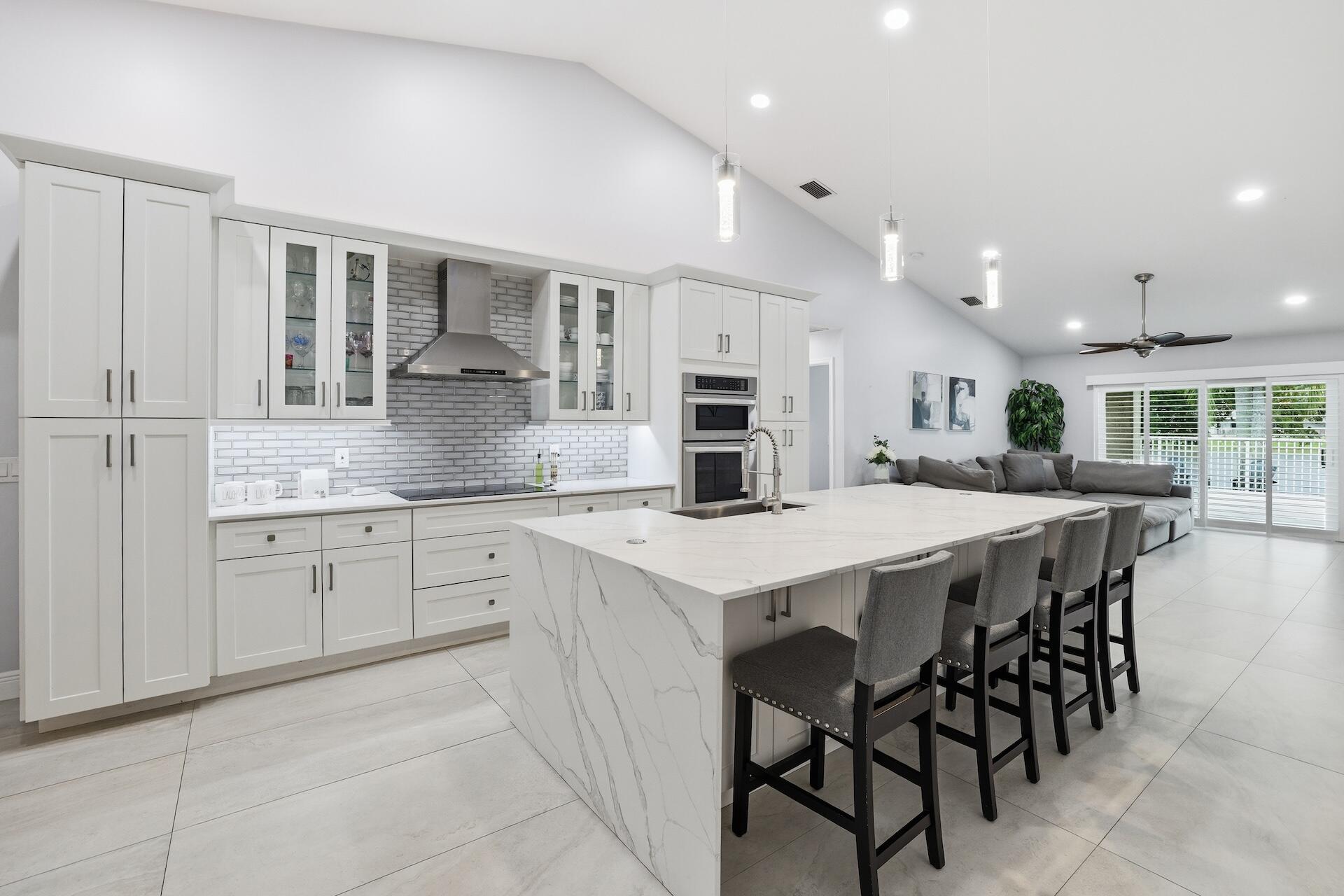 7403 Shell Ridge Terrace Lake Worth, FL 33467 - Photo 6 of 37 a kitchen with stainless steel appliances kitchen island granite countertop a table chairs sink and cabinets