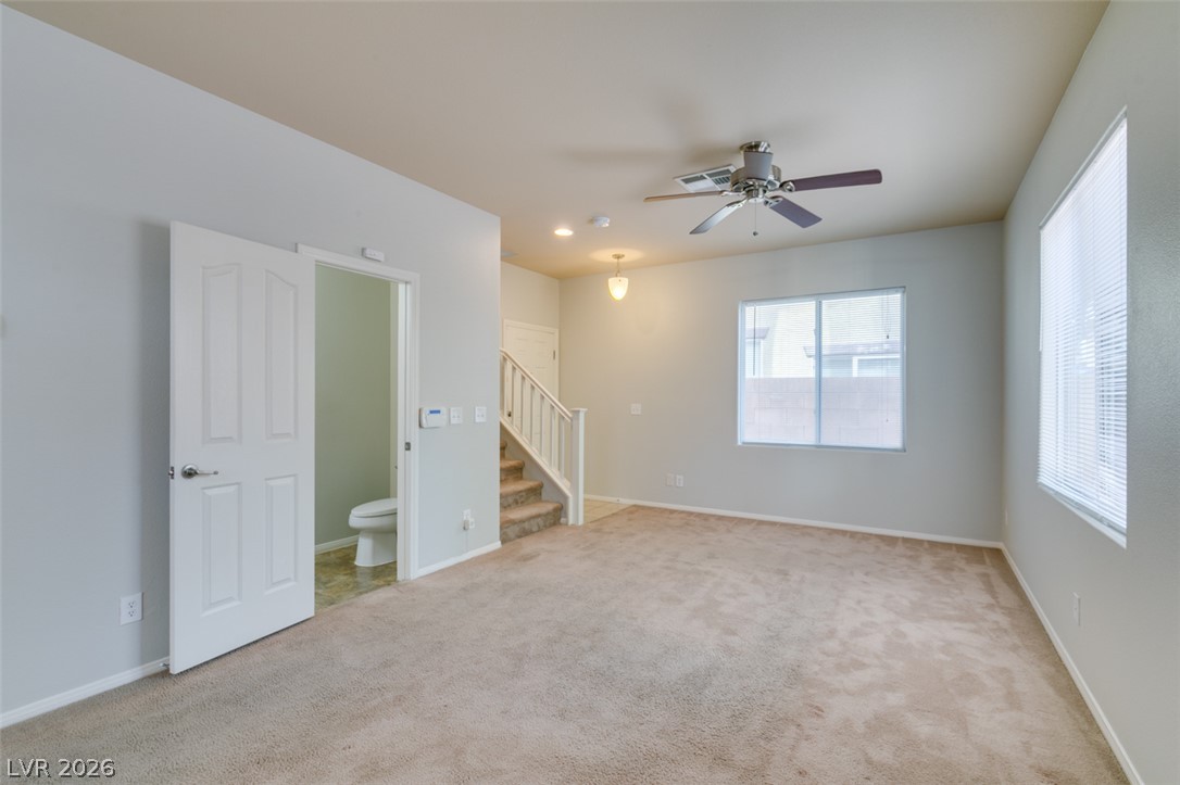 8937 Caledon Ridge Court Las Vegas, NV 89149 - Photo 8 of 43 A versatile living space with a ceiling fan, plush carpet, and convenient access to a powder room and staircase.