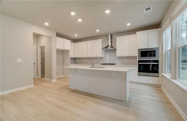 a large kitchen with kitchen island a sink a stove a refrigerator and white cabinets