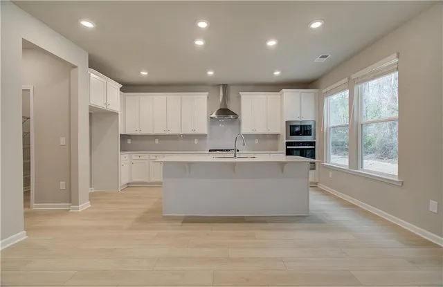 a large kitchen with kitchen island a sink a center island stainless steel appliances and a window