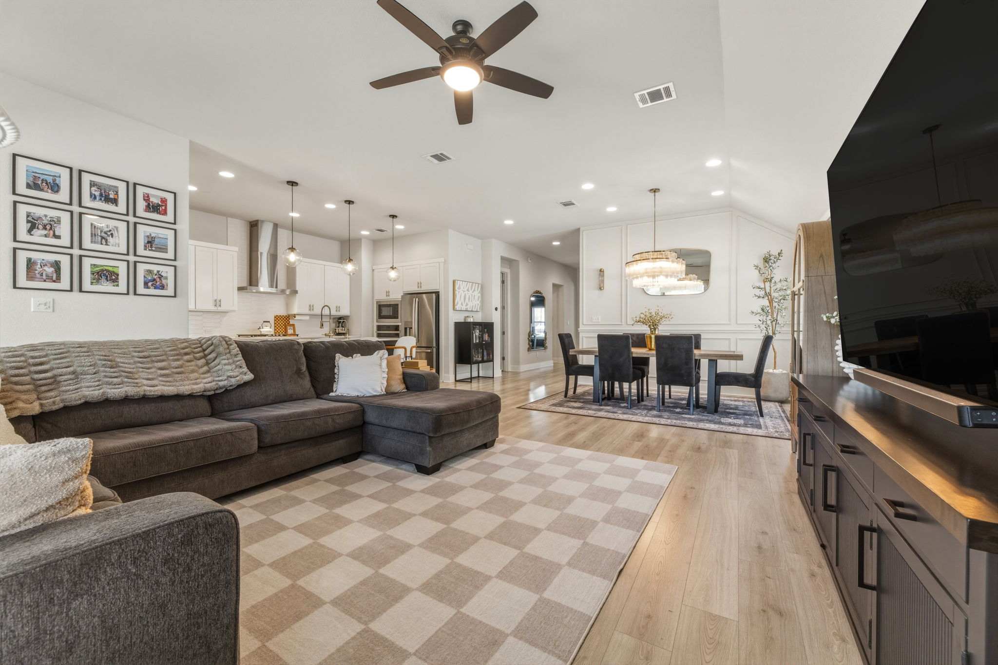 4505 Post Loop Round Rock, TX 78681 - Photo 13 of 40 Living room with light wood finished floors, a ceiling fan, a chandelier, and a decorative wall