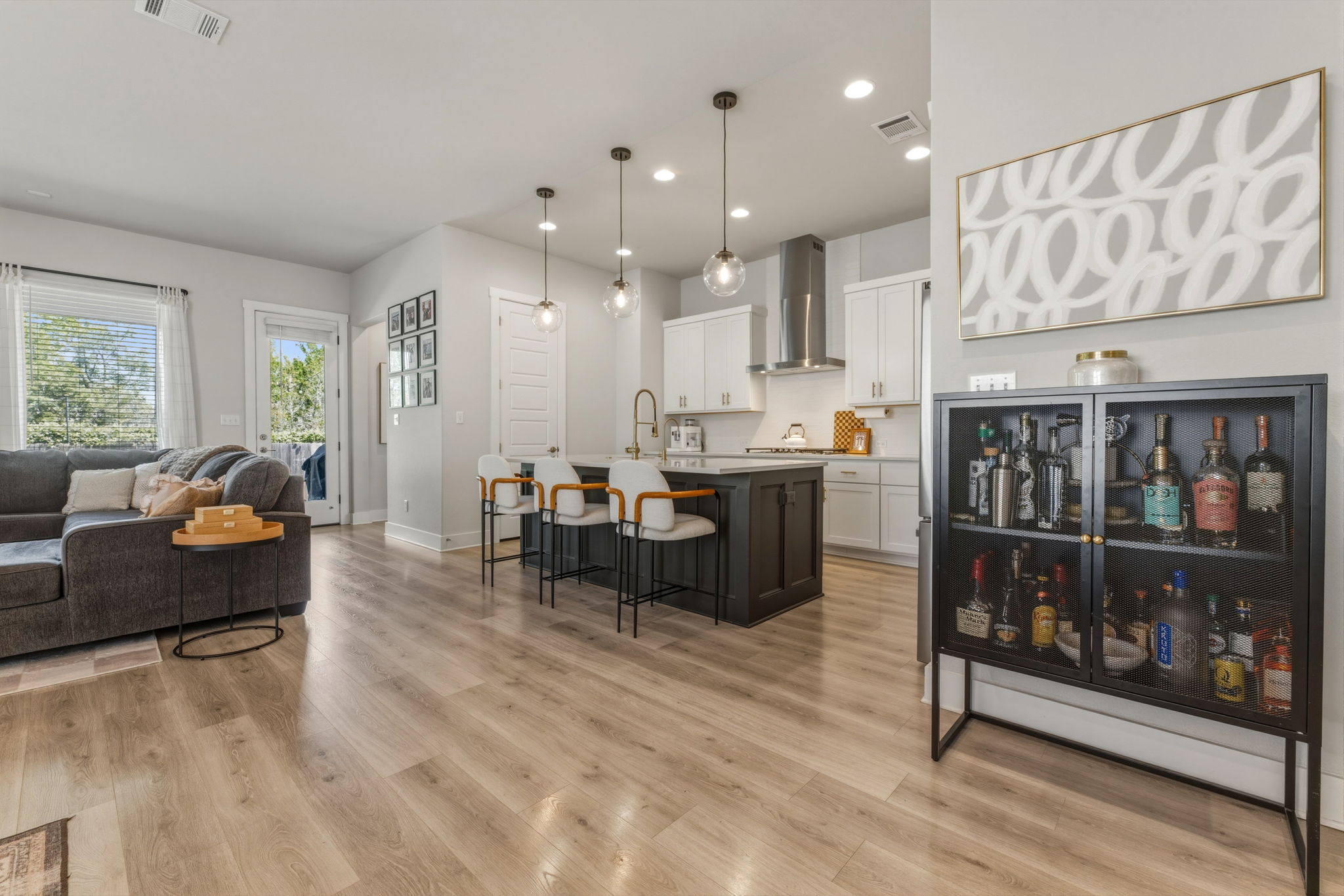 4505 Post Loop Round Rock, TX 78681 - Photo 39 of 40 Dual tone kitchen featuring open floor plan, decorative light fixtures, dual tone cabinets, a kitchen breakfast bar, and a kitchen island with sink