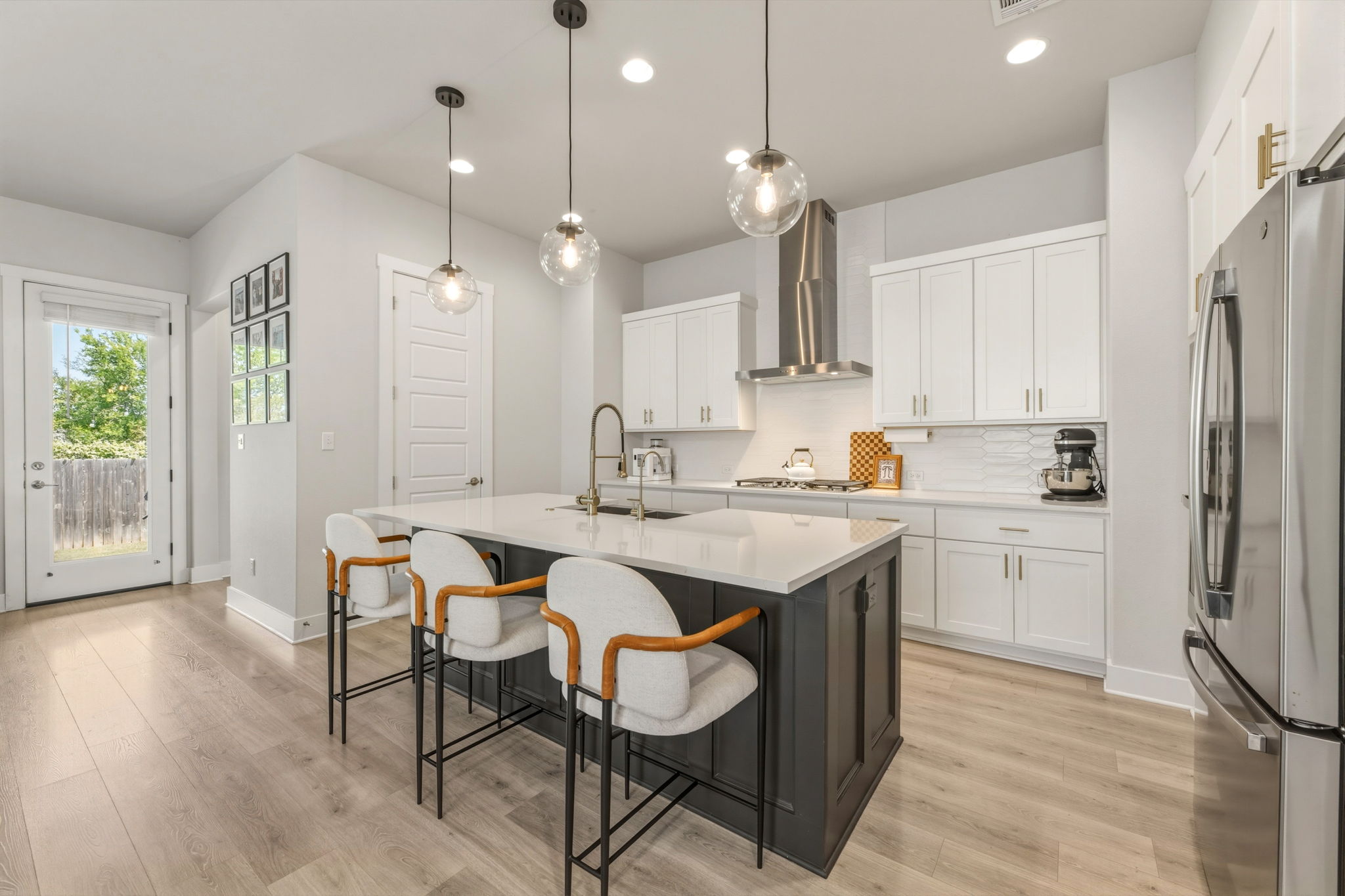 4505 Post Loop Round Rock, TX 78681 - Photo 15 of 40 Kitchen featuring stainless steel appliances, a kitchen breakfast bar, an island with sink, decorative light fixtures, and light wood-style floors