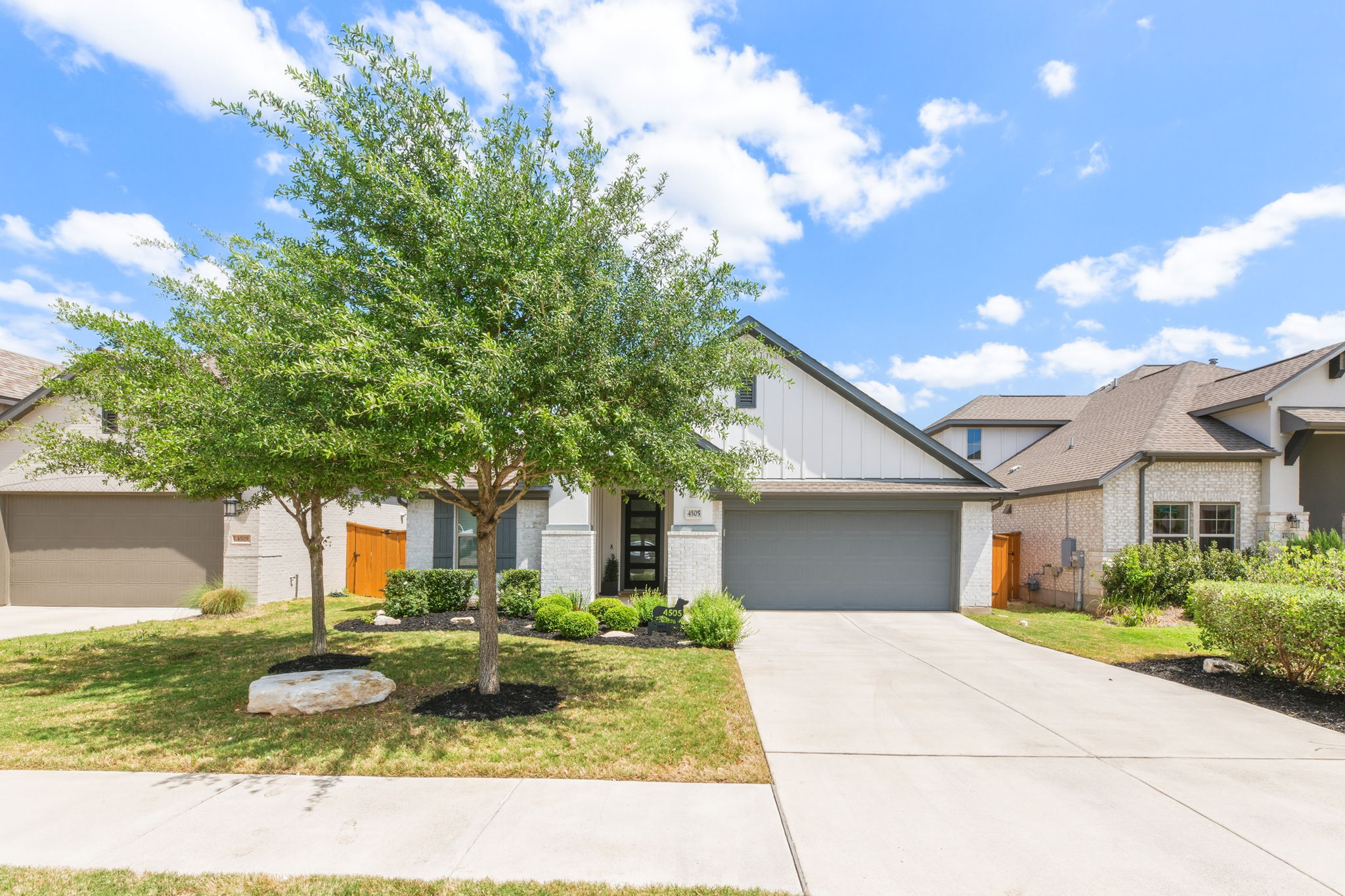 4505 Post Loop Round Rock, TX 78681 - Photo 2 of 40 View of front facade featuring board and batten siding, an attached garage, concrete driveway, and brick siding